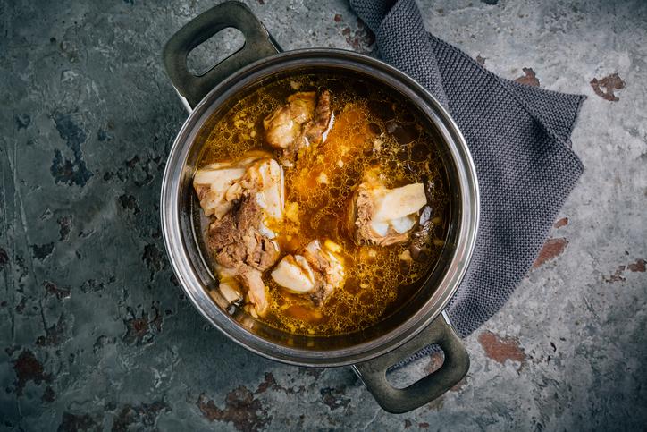 A steaming pot of homemade bone broth for dogs, filled with beef bones