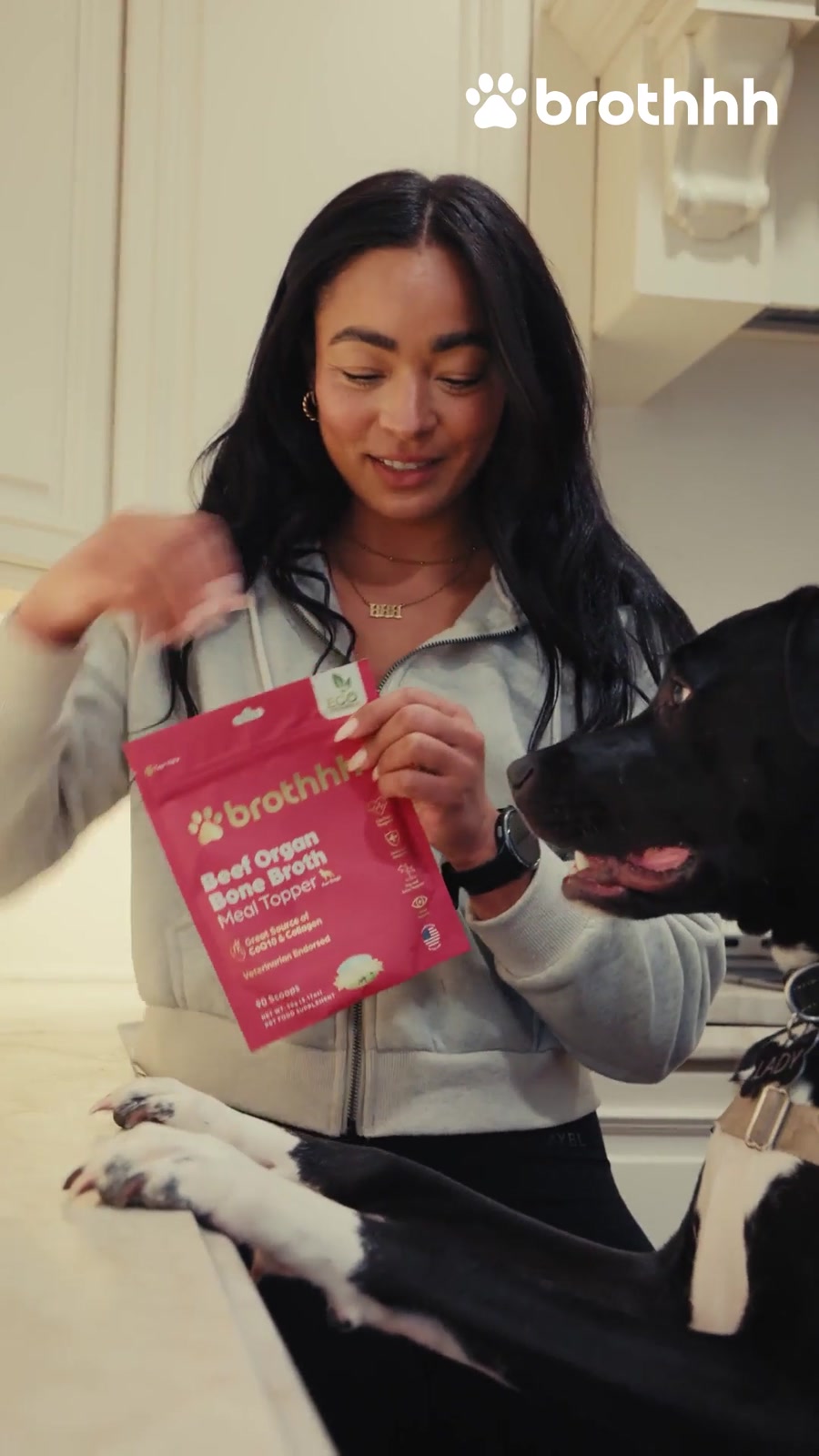 A creator holding The Meal Topper beside her excited dog